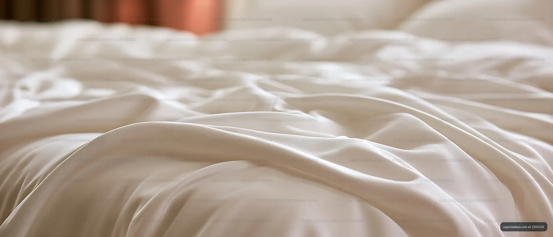 Elegant cream satin drapery on a softly lit bed