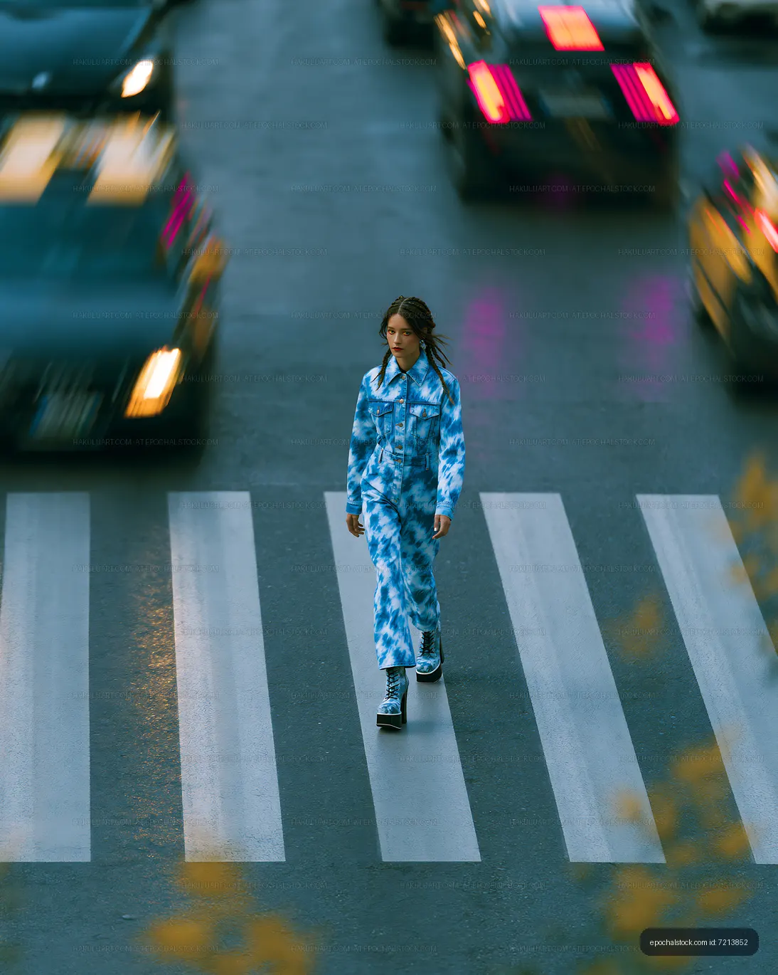 Woman in blue denim outfit walking on an urban crosswalk