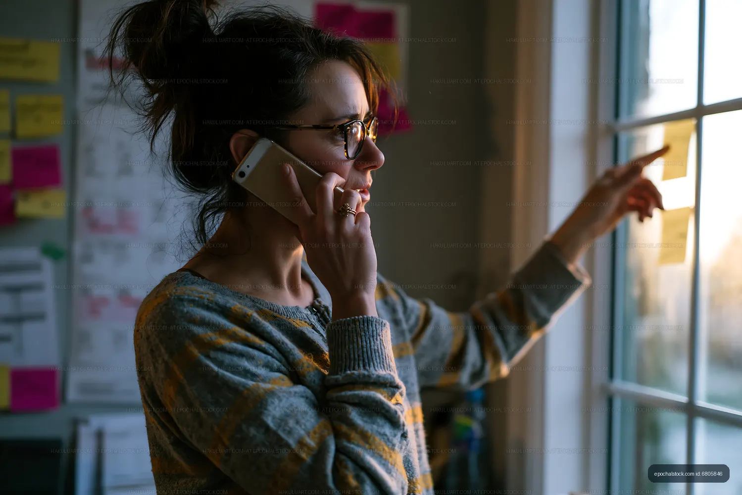 Woman talking on the phone while pointing at sticky notes on window