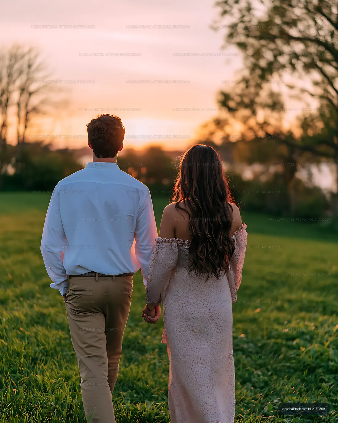 Two people walking together through a meadow at golden hour
