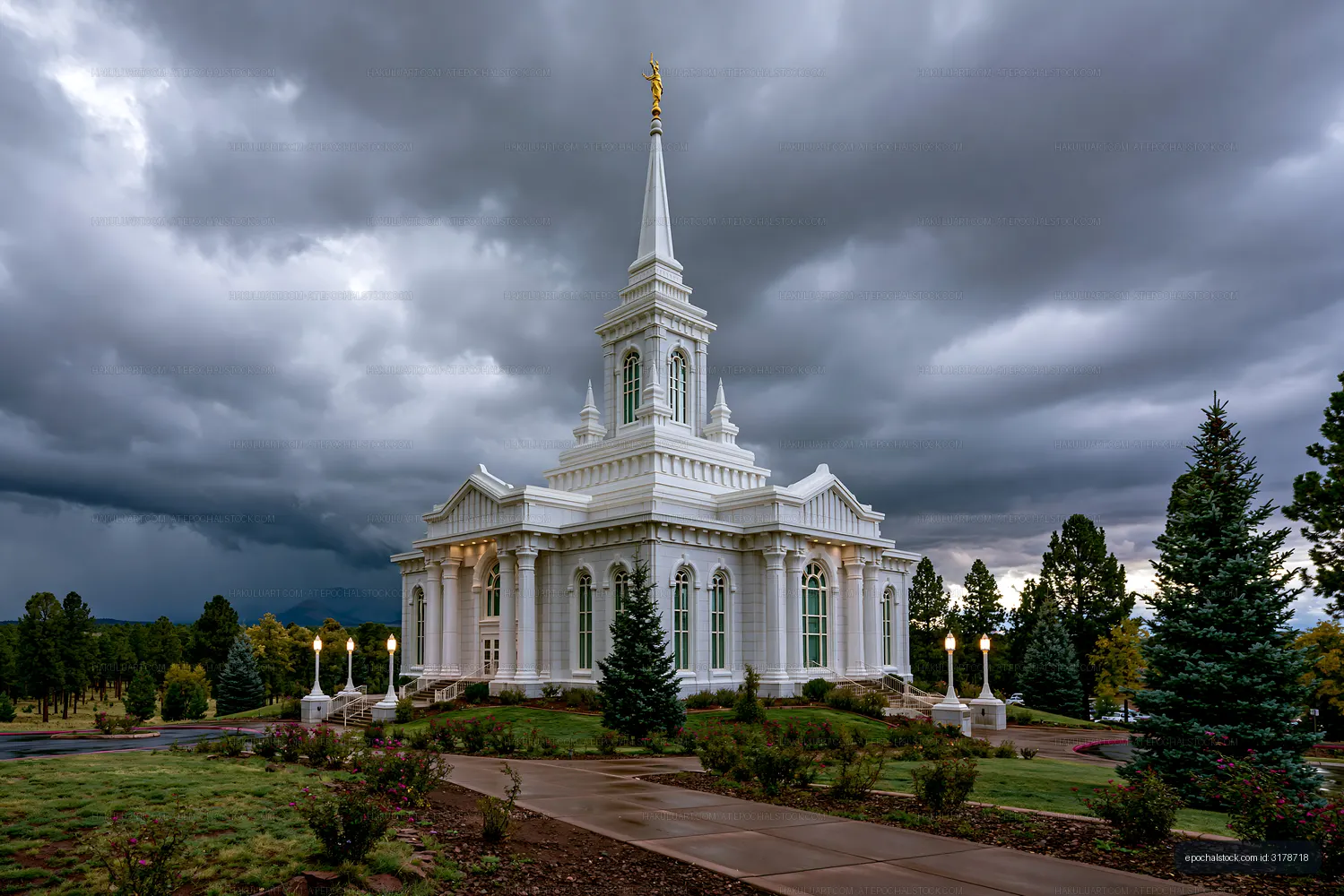White spired temple surrounded by trees and storm clouds