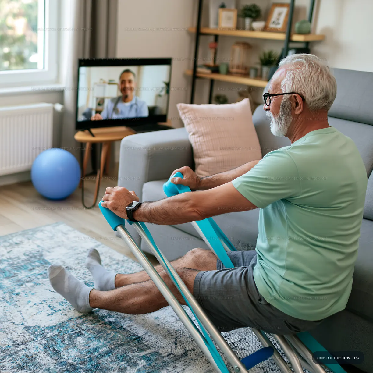 Senior man exercising at home while video calling with a trainer