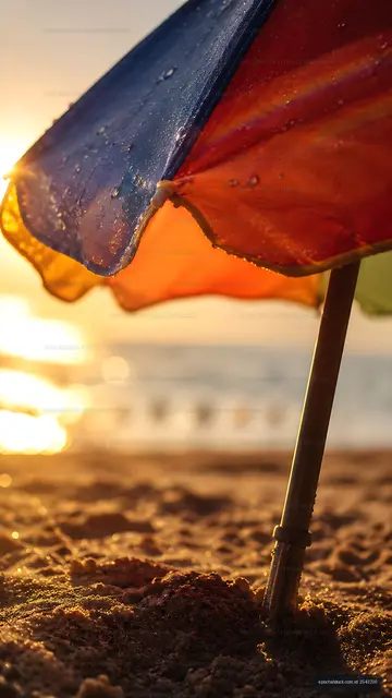 Colorful beach umbrella at sunset on sandy shore