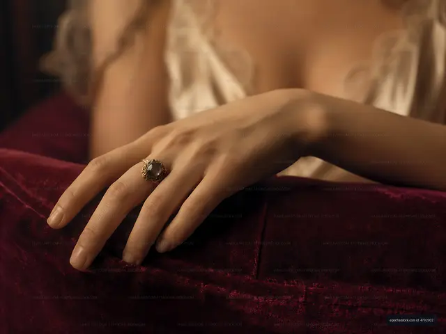 Hand with ring resting on plush fabric