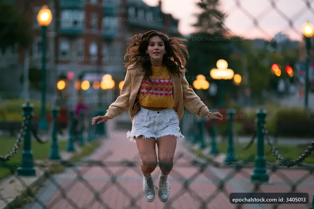 Woman jumps in the park during sunset
