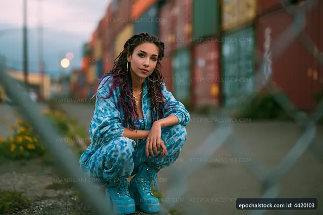Young woman posing near shipping containers in urban area