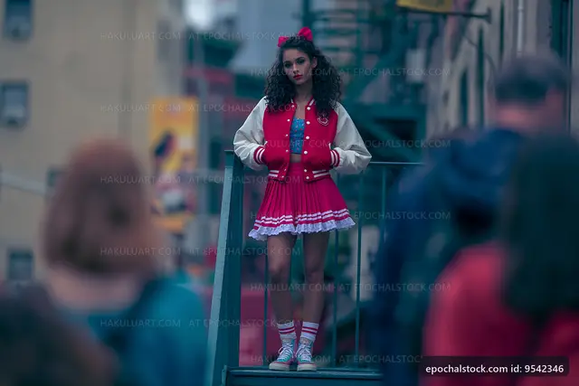 Young woman in a red dress and jacket stands on a city staircase