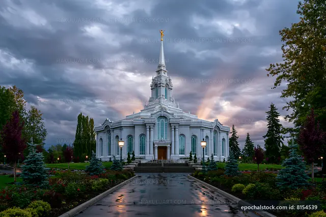 Church building with tall spire under cloudy sky at sunset