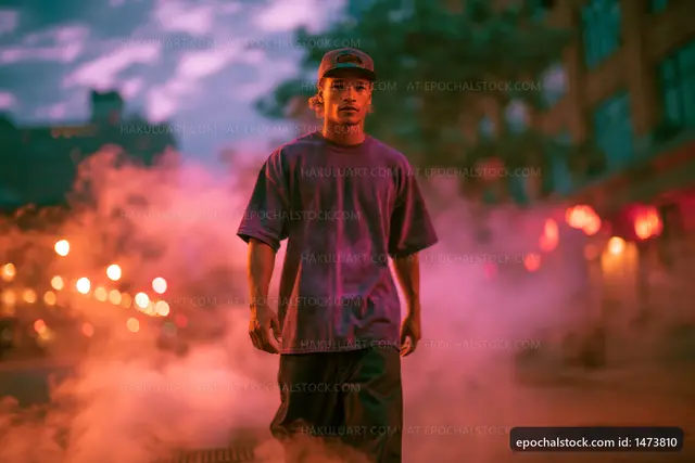 Young man walking through city street with smoke at dusk