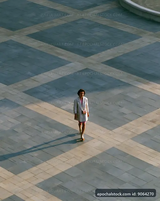 Person walking on a patterned pavement in a city square