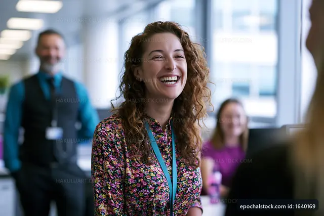 Happy woman chatting with colleagues in modern office setting