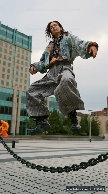Woman jumps over a chain in urban setting