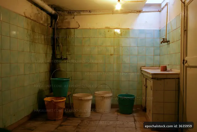 Old and worn bathroom with buckets in a tiled room