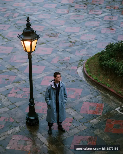 Man stands under a street lamp on a rainy day