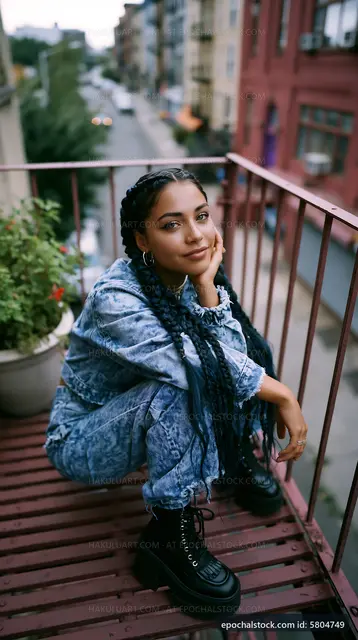 Young woman sitting on balcony with plants in urban setting