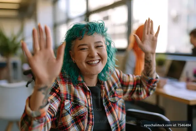 Smiling woman with blue hair waving in a bright office space