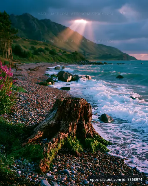 Sunlight breaking through clouds over rocky beach shore