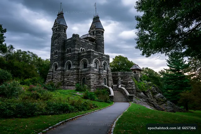 Historic stone castle surrounded by trees on a cloudy day