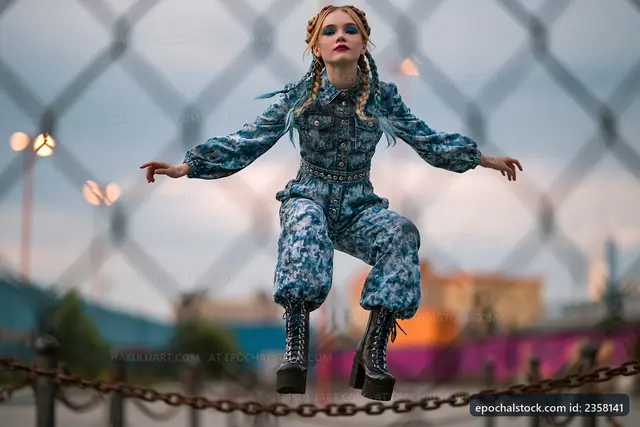 Girl jumps in blue outfit at urban park during sunset