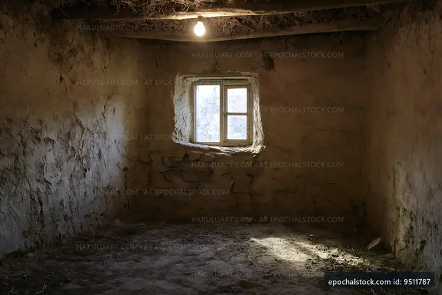 Light bulb hangs in an empty room with a small window