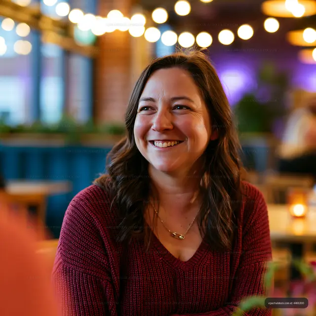 Woman smiling in a cafe with warm lighting and decorative plants