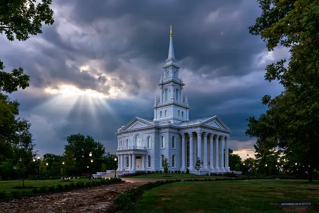 Historic white church under dark clouds with sun rays