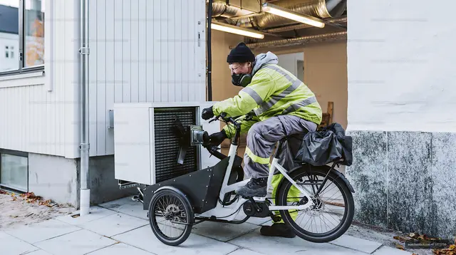Delivery worker using cargo bike with portable cooler outside building