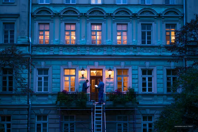 Workers renovating building exterior at night