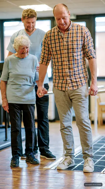 Caregiver assists elderly person during physical therapy session