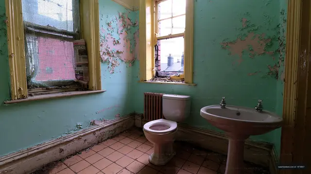 Old bathroom with peeling paint and broken windows