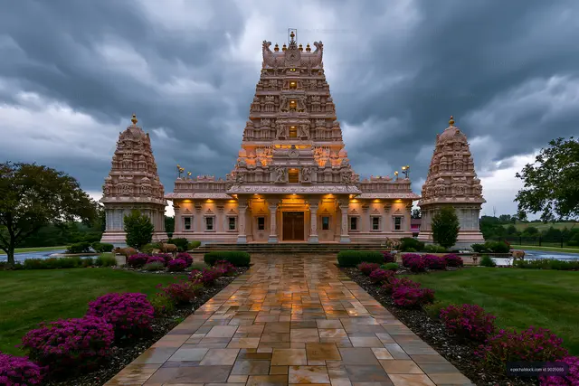 Hindu temple under cloudy skies with gardens in view