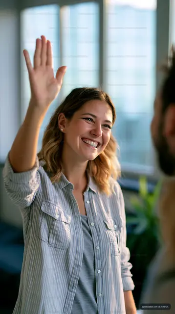 Smiling woman waving hello in a bright indoor setting