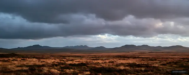 Dramatic storm clouds over a mountain grassland panorama