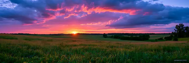 Panoramic rural fields beneath a dramatic sunset