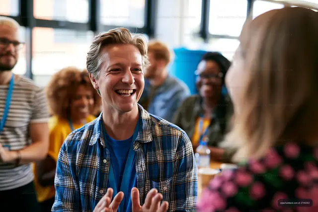 Smiling man gesturing during conversation in a bright indoor gathering