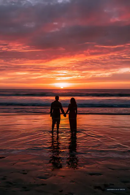 Romantic ocean sunset with couple holding hands