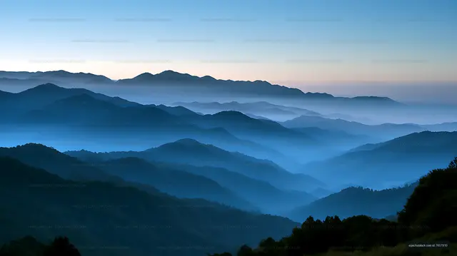 Blue mountain ridges fading into dawn mist