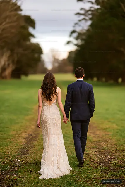 Bride and groom walking away through a tree-lined park
