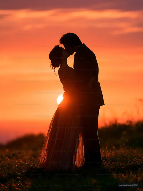 Couple embracing and kissing against a glowing sunset