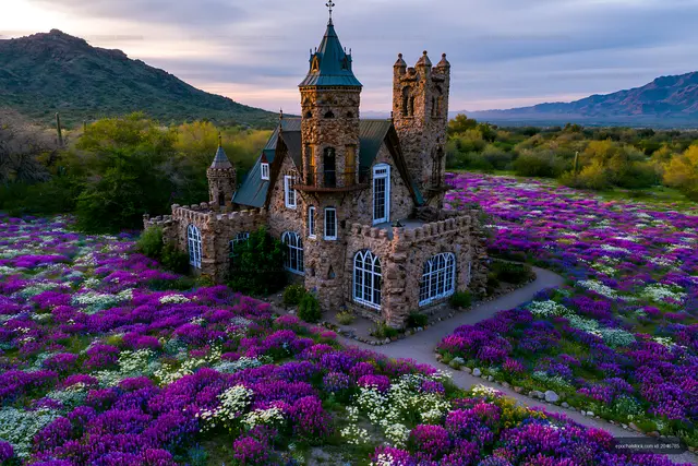 Stone castle among purple wildflowers and desert mountains