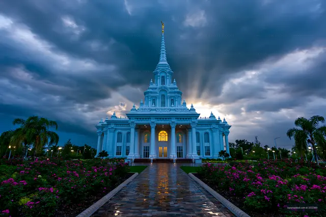 Illuminated ornate temple with reflective path and storm clouds