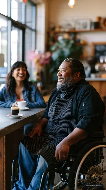 Joyful cafe conversation with chef seated in wheelchair