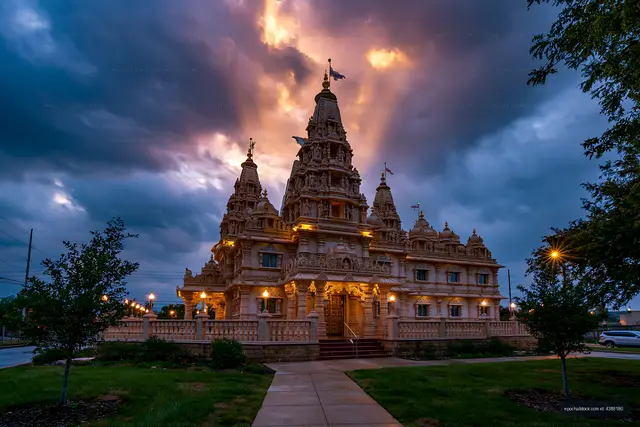 Ornate temple glowing under a dramatic sunset sky